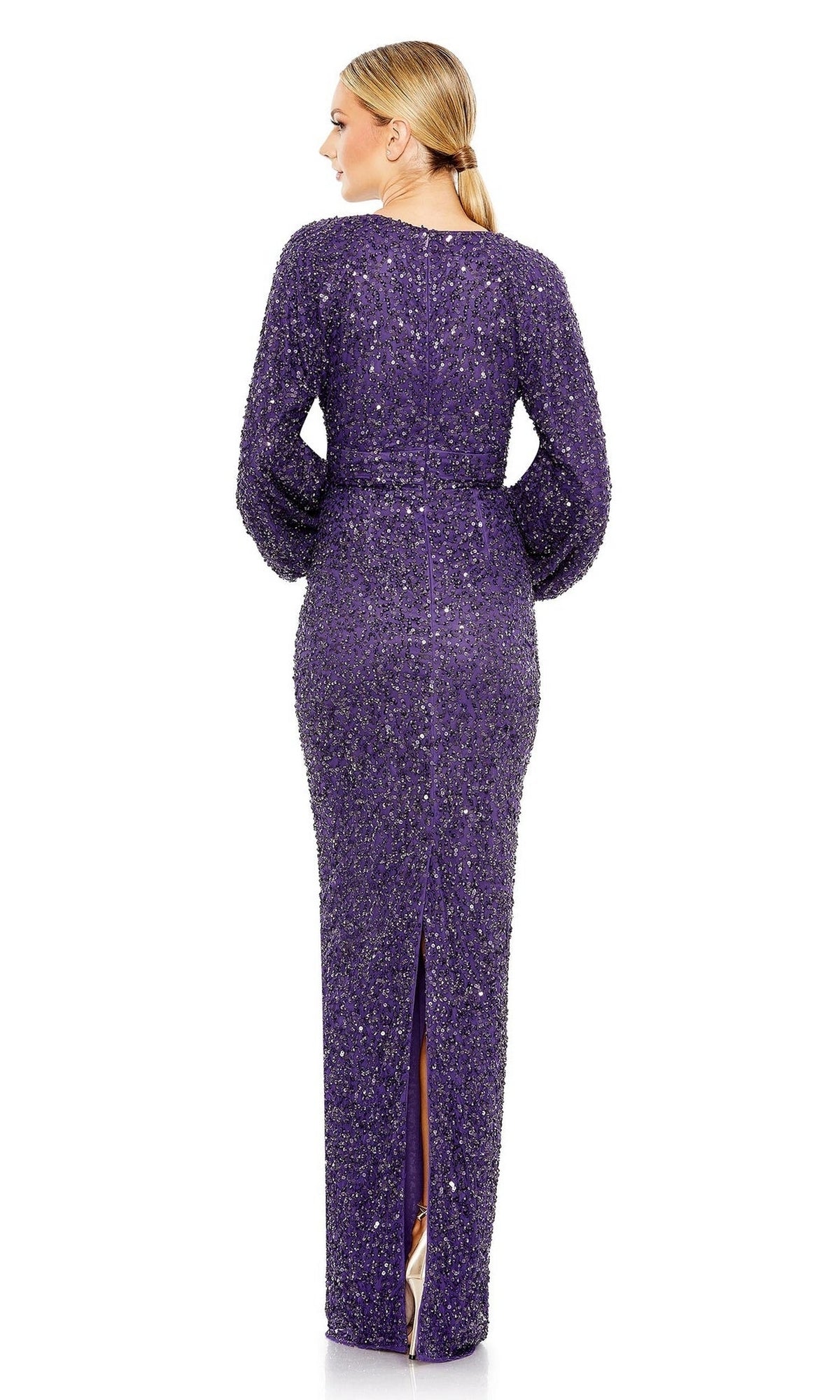 A woman faces away in the Mac Duggal 10791 Sequin Long Sleeve Formal Gown, a floor-length purple sequin dress with a back slit; her hair is styled in a low ponytail.